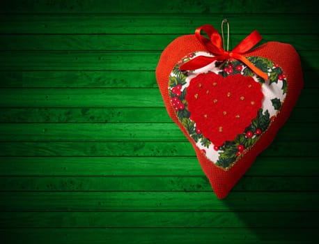 Christmas heart, red, white and green hanging on green wooden wall with shadows