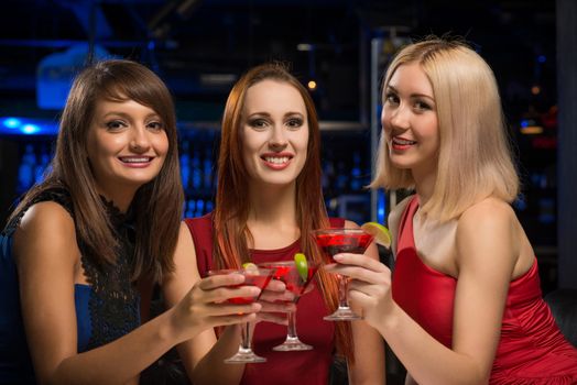 three girls raised their glasses in a nightclub, have fun with friends