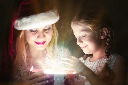 mother in Santa Claus cap and daughter opened a box with Christmas gift boxes of shining light and magic