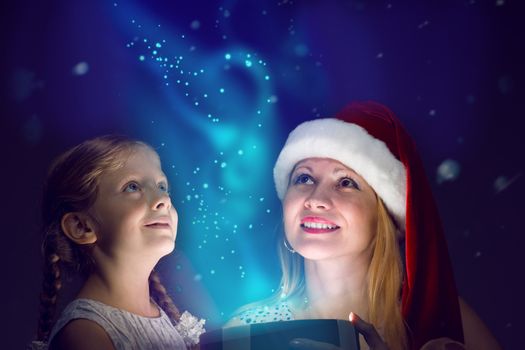 mother in Santa Claus cap and daughter opened a box with Christmas gift boxes of shining light and magic