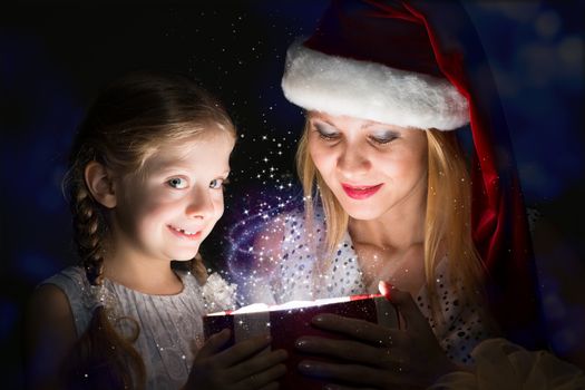 mother in Santa Claus cap and daughter opened a box with Christmas gift boxes of shining light and magic