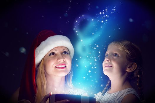 mother in Santa Claus cap and daughter opened a box with Christmas gift boxes of shining light and magic