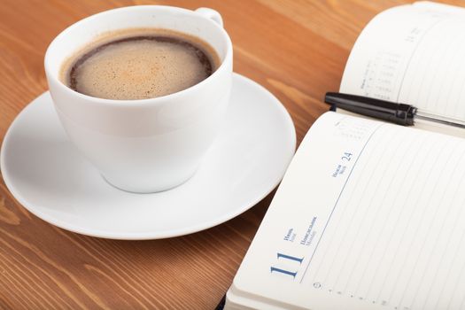 Notebook with pen and cup of coffee on a table. Top view