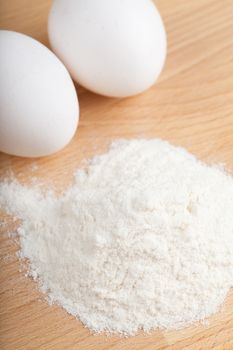 Closeup view of eggs and flour on a wooden table