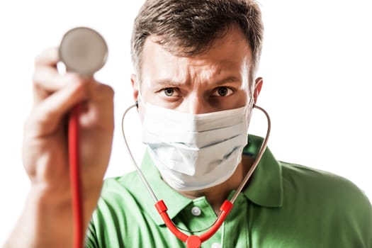 Desperate doctor with surgical mask in green shirt holding his stethoscope