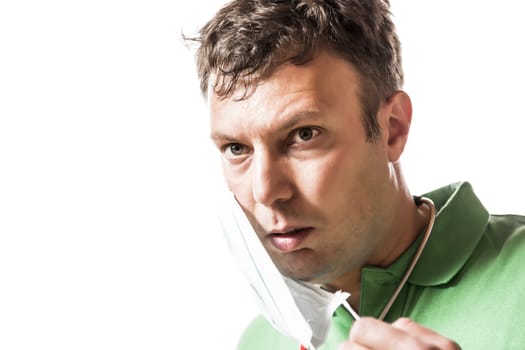 Exhausted and sweaty doctor in a green t-shirt with a red stethoscope and surgical mask