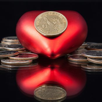 Red heart and U.S. dollar coins on a black table