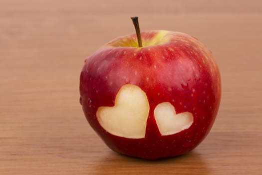 Two hearts on the fresh apple, a Valentine theme - on the wooden background