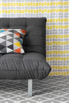 Sofa with colorful cushion, on bright floral background.