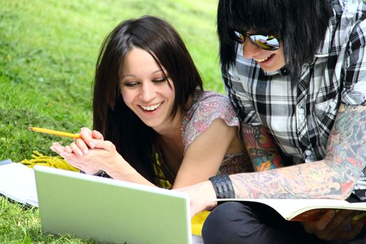 Couple of students studying outdoor with laptop