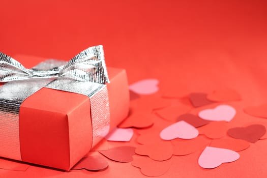 Valentines Day gift in box and small hearts on red background