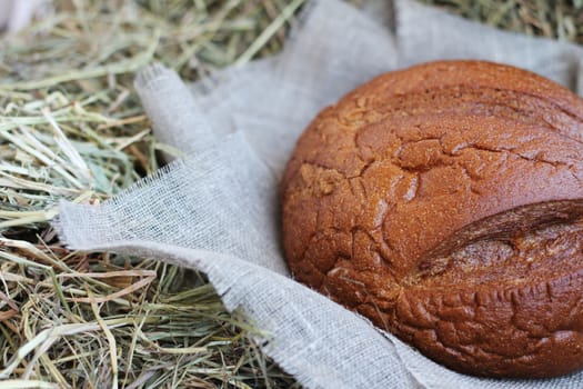 Brown fresh bread and flax textile on hay