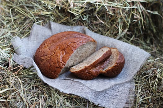 Brown fresh sliced bread and flax textile on hay