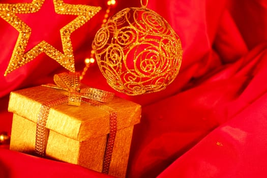 Golden christmas decoration and gift on red fabric background