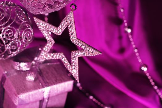 Silver christmas decoration and gift on purple fabric background
