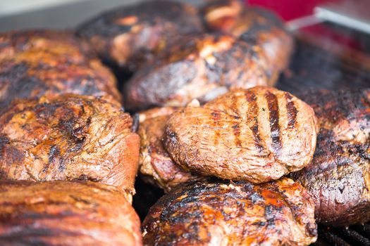 Several grilled boneless rib-eye steaks on a barbecue resting