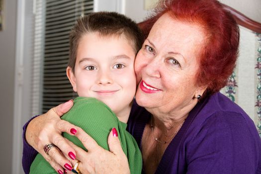 Grandmother's Love to her eight years old grandson, she hugs him tighly with a cheek to cheek touch while looking at you