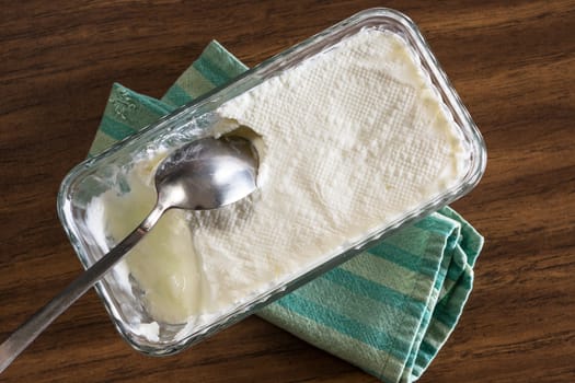 Homemade yogurt ready to serve on a green striped cloth on the table with a spoon in it