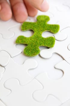 hand holding a green puzzle piece, green space concept