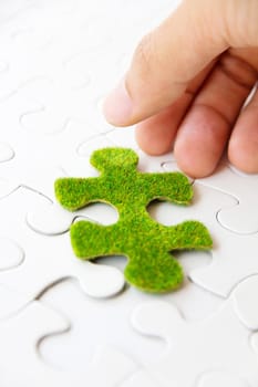 hand holding a green puzzle piece, green space concept