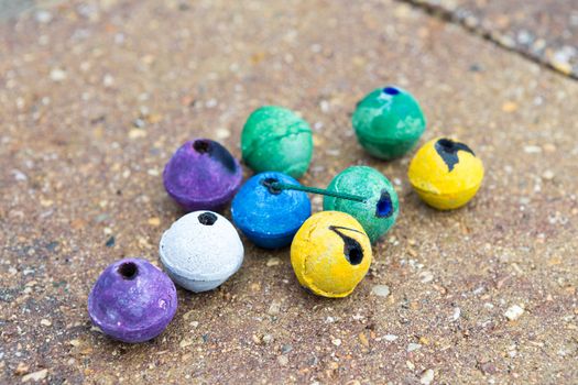 Colorful round smoke bombs naturally on the paver street some of them used some of them not. They have purple, green, yellow, white and blue colors, surely someone having fun