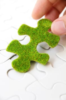 hand holding a green puzzle piece, green space concept