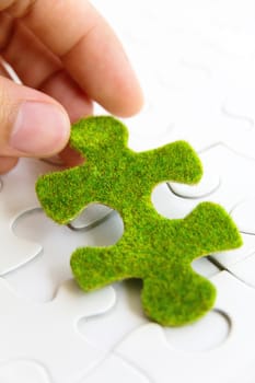 hand holding a green puzzle piece, green space concept