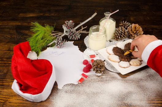 Santas hand taking a cookie next to the wish list