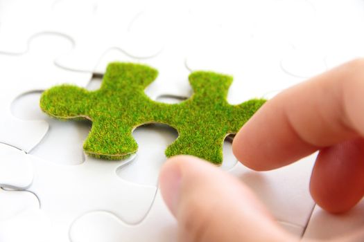 hand holding a green puzzle piece, green space concept