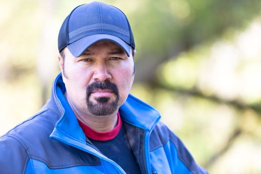 Man with a goatee looking determined attitude on a green sunny background