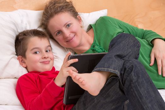 Learning with comfort from his mother in the bed on the laptop