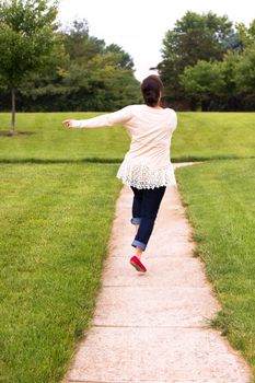 Happy lady cannot hide her feelings, shes is skipping happily with her arms on the side, she is wearing lace shirt and jeans along with her red shoes