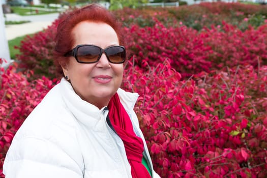 Senior lady enjoying the autumn around burning bushes