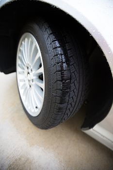 Wet automobile tire, on a concrete pavement, treads are showing clearly with rain in them