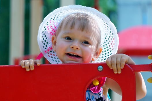 Two-year-old girl with hat smiling and looking away                     