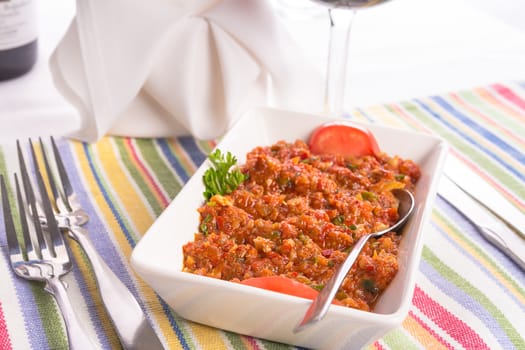 Meze, diced tomatoes with parsley, walnuts and hot red peppers seasoned with lemon juice served on a colorful  placemat