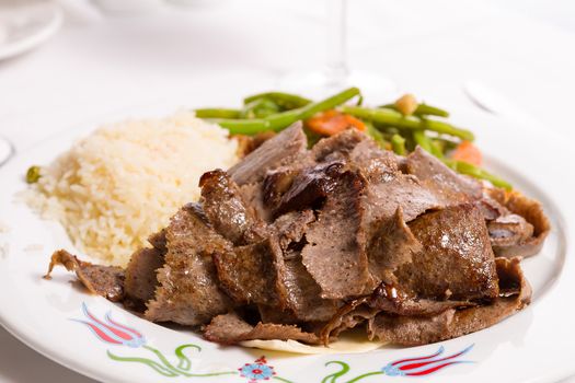 Gyro doner garnished with rice pilaf and vegetables served on thin lavash bread