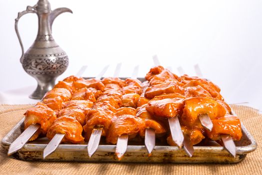 Well seasoned cicken skewers are waiting on aluminum tray, ready to go on to the grill and cook