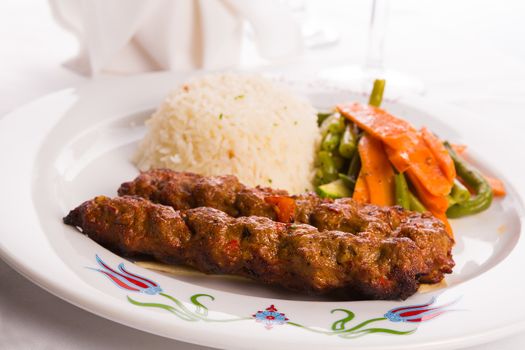 Turkish Adana Kebap with rice pilaf and vegetables served on a Plate