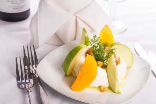 Strained yogurt labneh citrus salad with peeled oranges and green apples garnished with dill and walnuts served with oil