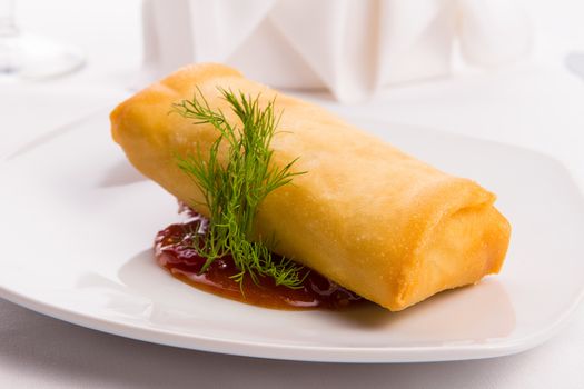 Spring roll complimented with dill served with sweet and sour sauce elegantly