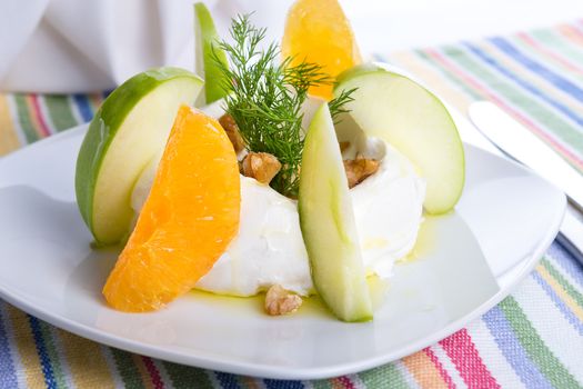 Strained yogurt labneh citrus salad with peeled oranges and green apples garnished with dill and walnuts served with oil