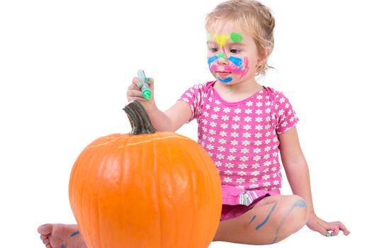 Pretty toddler girl painting the big orange pumpkin for Halloween