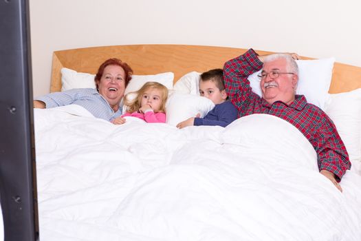 Grandparents watching TV in the bed with their grand kids, they look excited, perhaps its an adventure movie