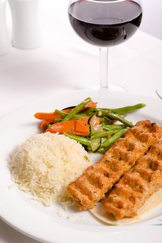 Chicken Adana kebap served with rice pilaf and green vegetables and some carrots, complimented with red Vine and water