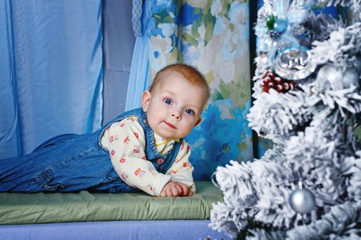 Redhead babe with blue eyes lies near Christmas tree