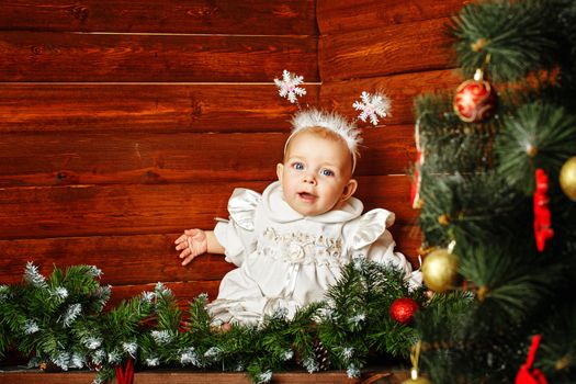 Cute little girl dressed as snowflakes near the Christmas tree and decorations