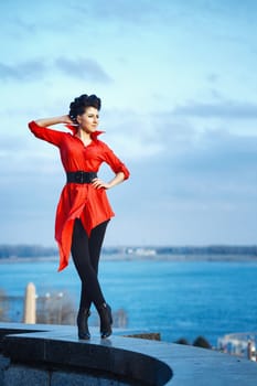 Attractive girl in red shirt walking along waterfront