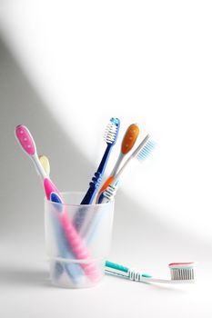 Some toothbrushes in a plastic glass