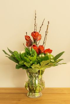 glass vase with red Amaryllis  green leaves and white roses